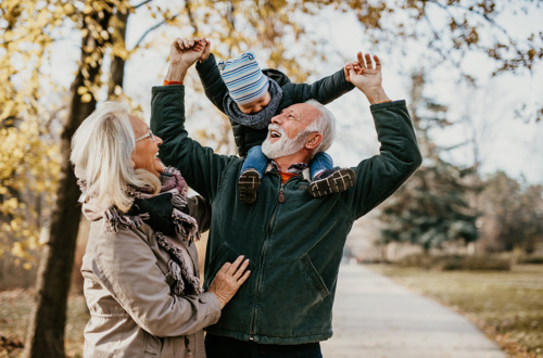Grandparents walking and laughing with their grandson at a park