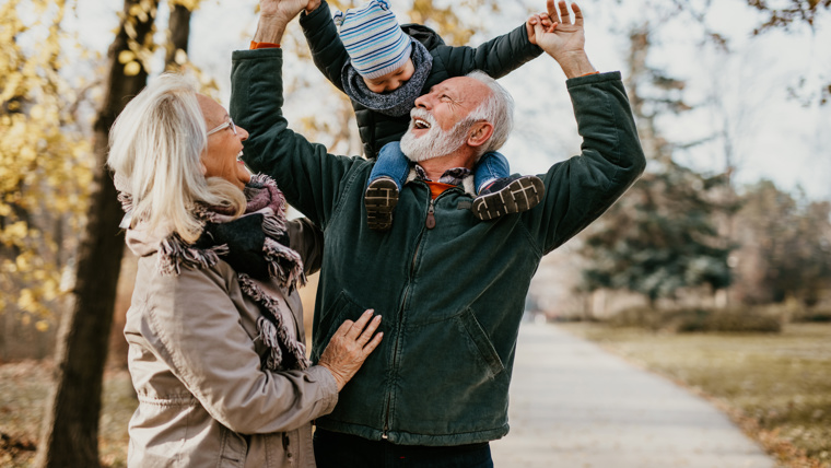 Grandparents walking and laughing with their grandson at a park